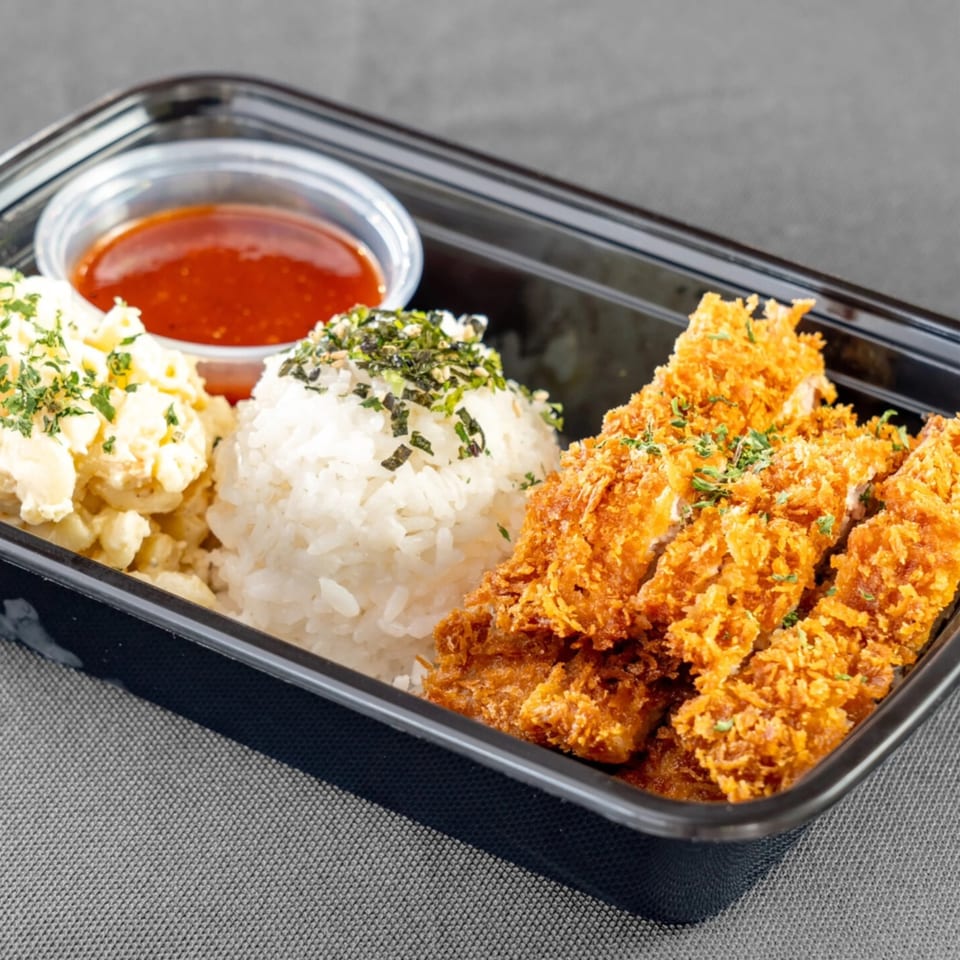 Da Kane's Kitchen's American plate lunch with crispy fried chicken, rice, macaroni salad, and sauce.